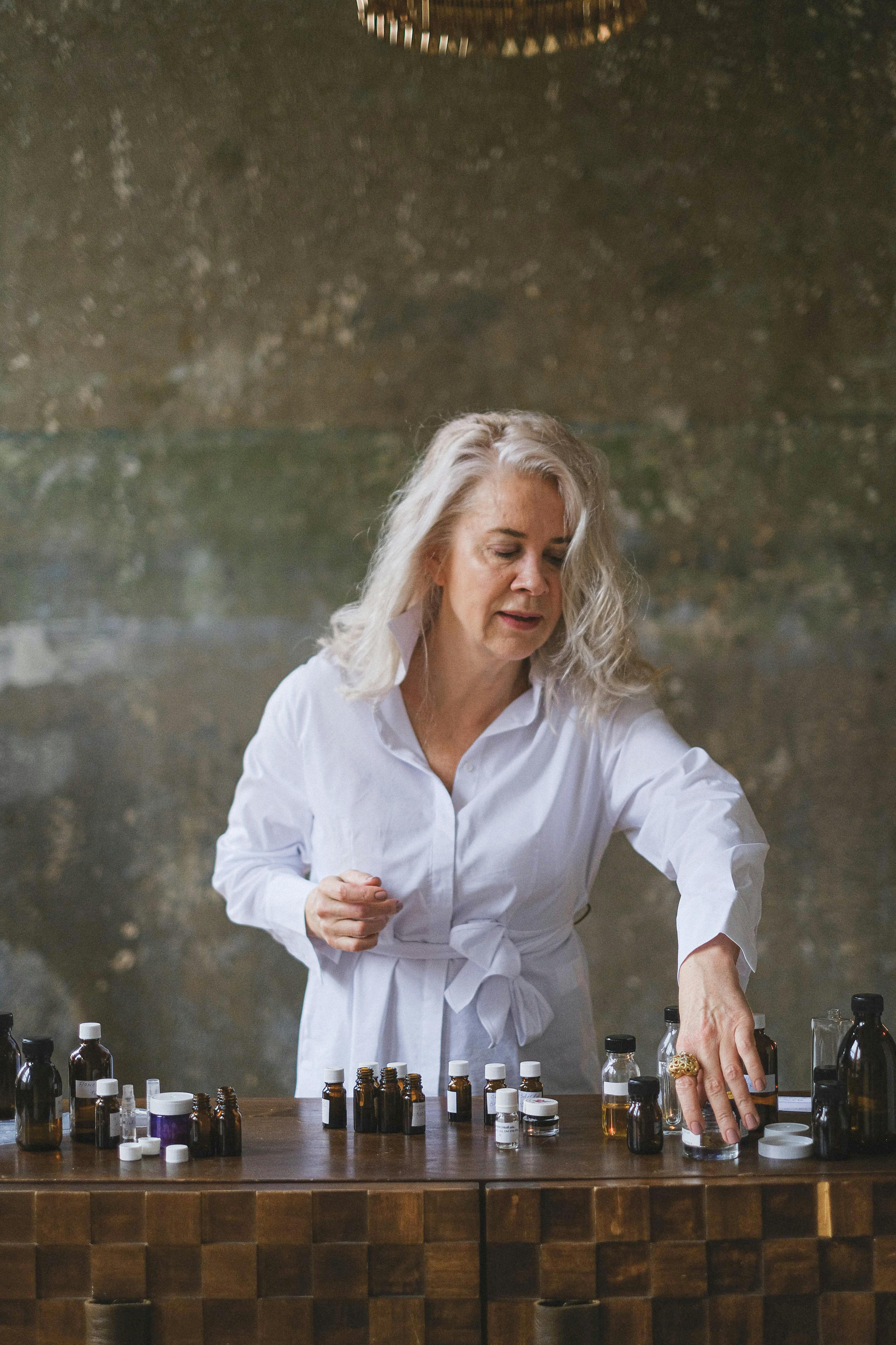 Senior adult woman organizing bottles on a wooden table with an artistic background.