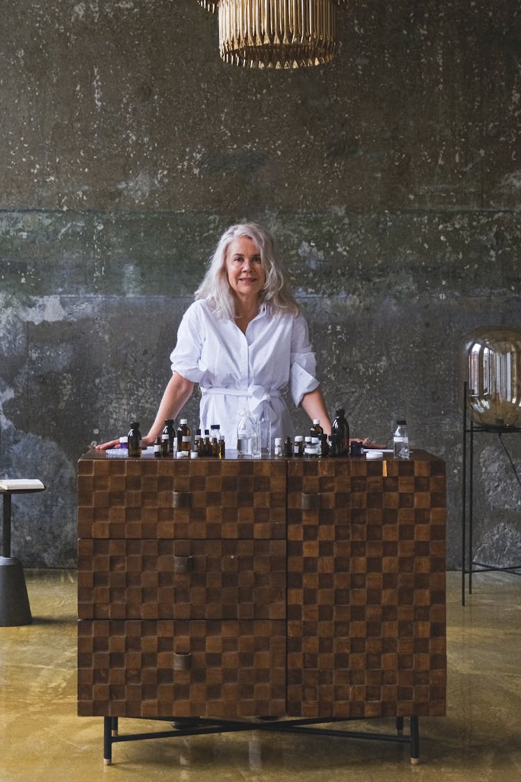 Senior Woman Standing Behind A Dresser With Empty Medication Bottles