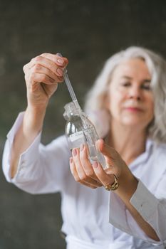 一位穿着实验服的老妇人正在用吸管进行科学研究