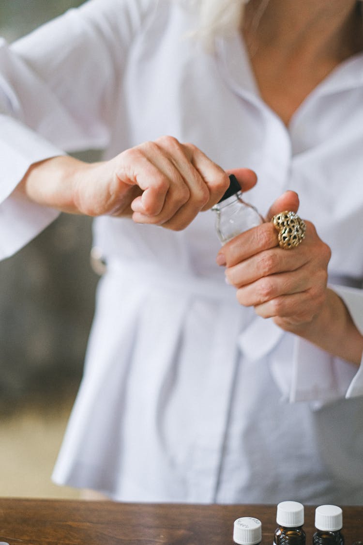 Woman In A White Shirt Opening A Small Bottle