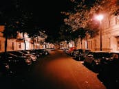 夜晚的城市街道十分安静，两旁停满了汽车，旁边是住宅楼