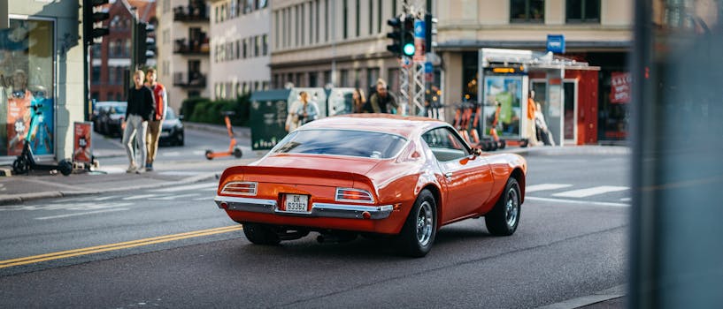 Vintage red Pontiac car driving through a busy city street, capturing classic automotive nostalgia.
