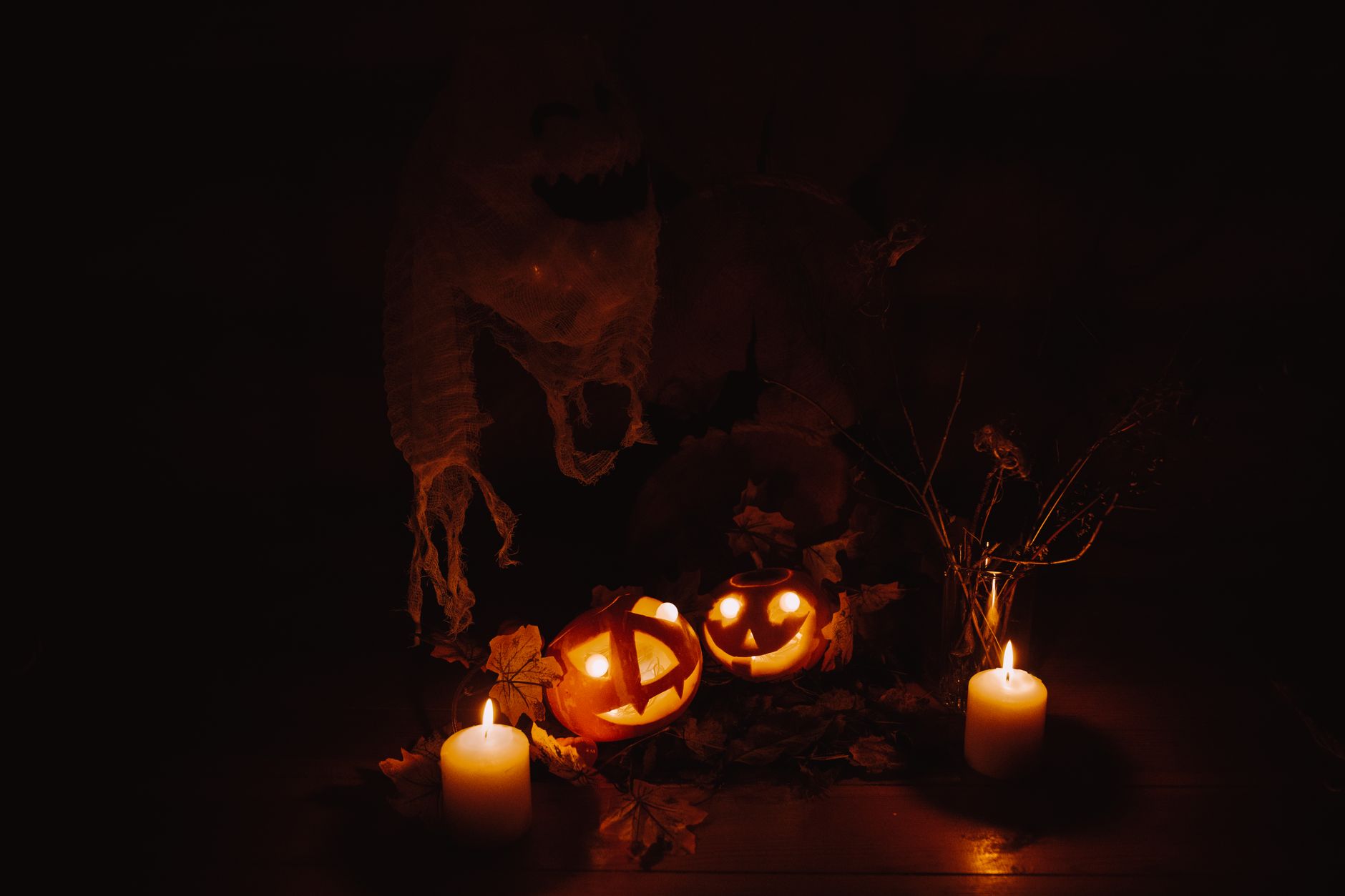 Moody Halloween display with glowing pumpkins and candles casting eerie shadows. — free online jigsaw puzzle on JigsawPuzzlesFreeOnline.org