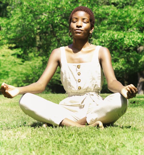 Woman in White Dress Meditating on Grass