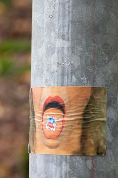 Unique art poster displaying a mouth with a cube, attached to a street pole.