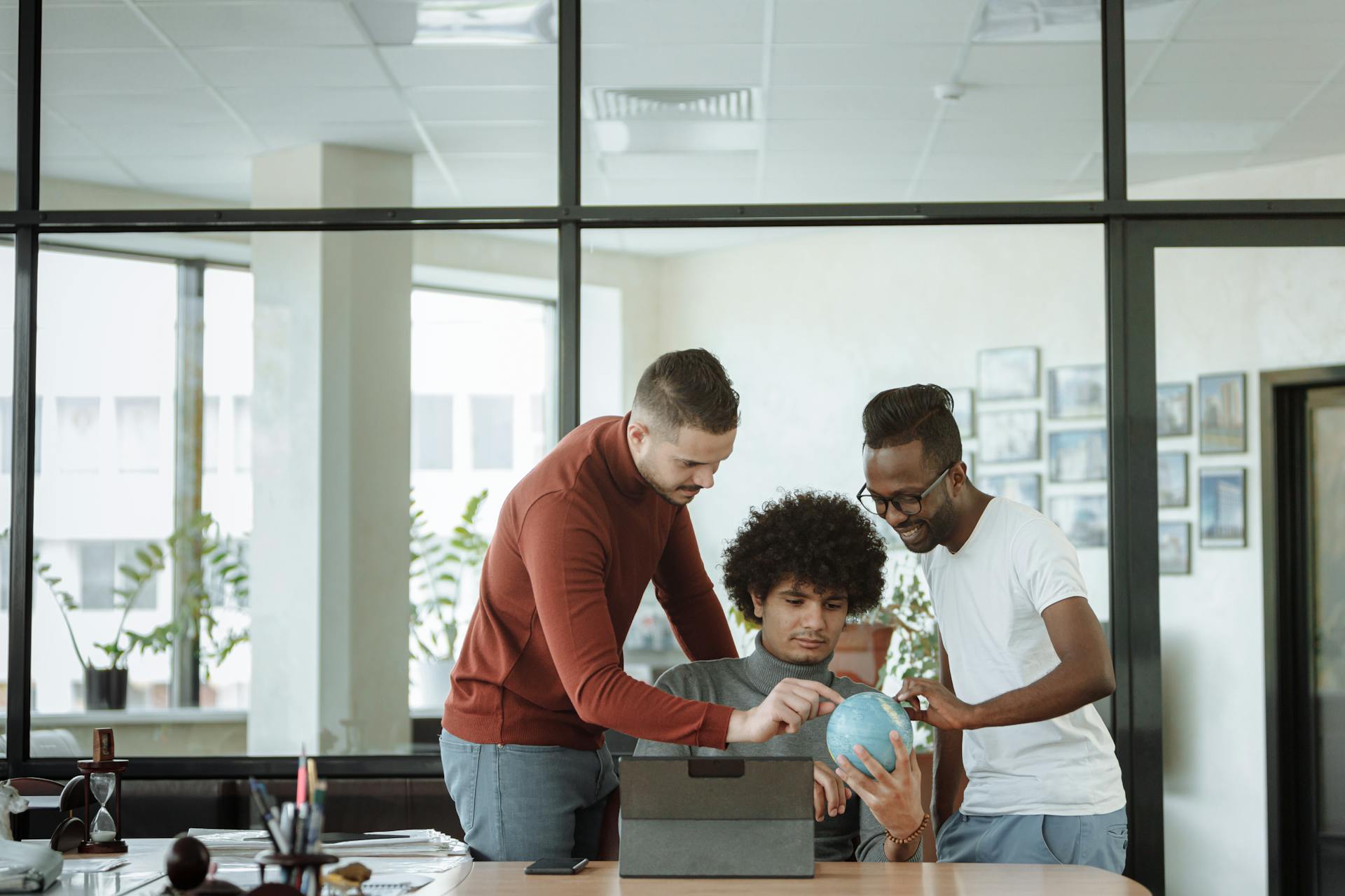 Young professionals gathered around a desk, discussing ideas with a globe, symbolizing global collaboration.