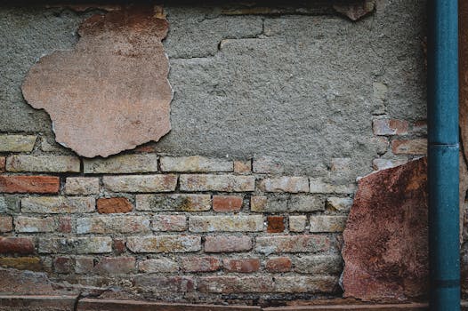 A vintage brick wall with rough, weathered texture and peeling plaster. Captures a sense of decay.