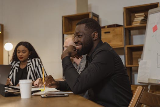 A diverse group of professionals in an office meeting, sharing ideas and smiling.