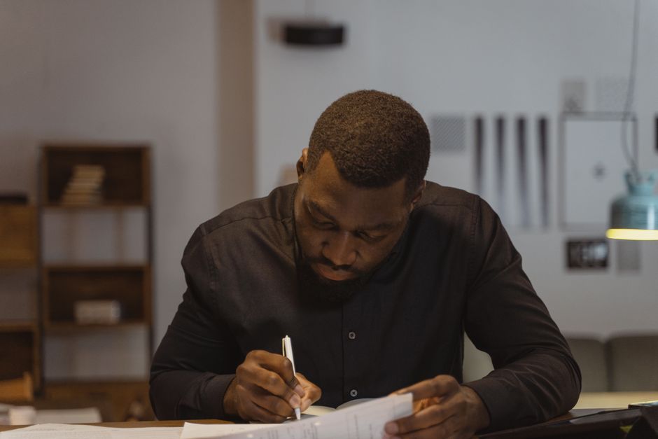 A man diligently writing notes in a modern office environment. Perfect for business and productivity themes. A man diligently writing notes in a modern office environment. Perfect for business and productivity themes.