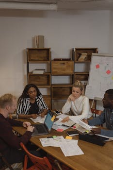 A diverse team engaged in a project discussion around a table in a modern office setting.