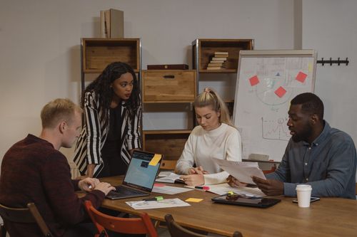 Free A multicultural team collaborating in a modern office setting with laptops and graphs. Stock Photo