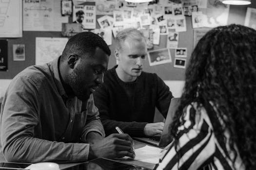 A diverse group engaged in a planning meeting, collaborating on laptops and notes.