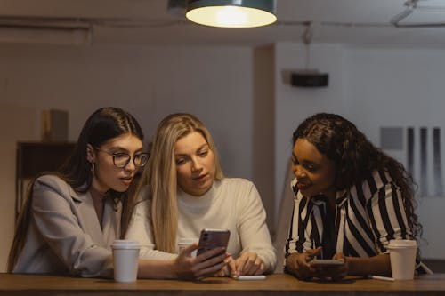 Women Sitting Beside Each Other Looking at Phone