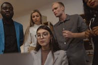 一群专业人士在现代办公环境中围绕笔记本电脑进行团队合作与协作