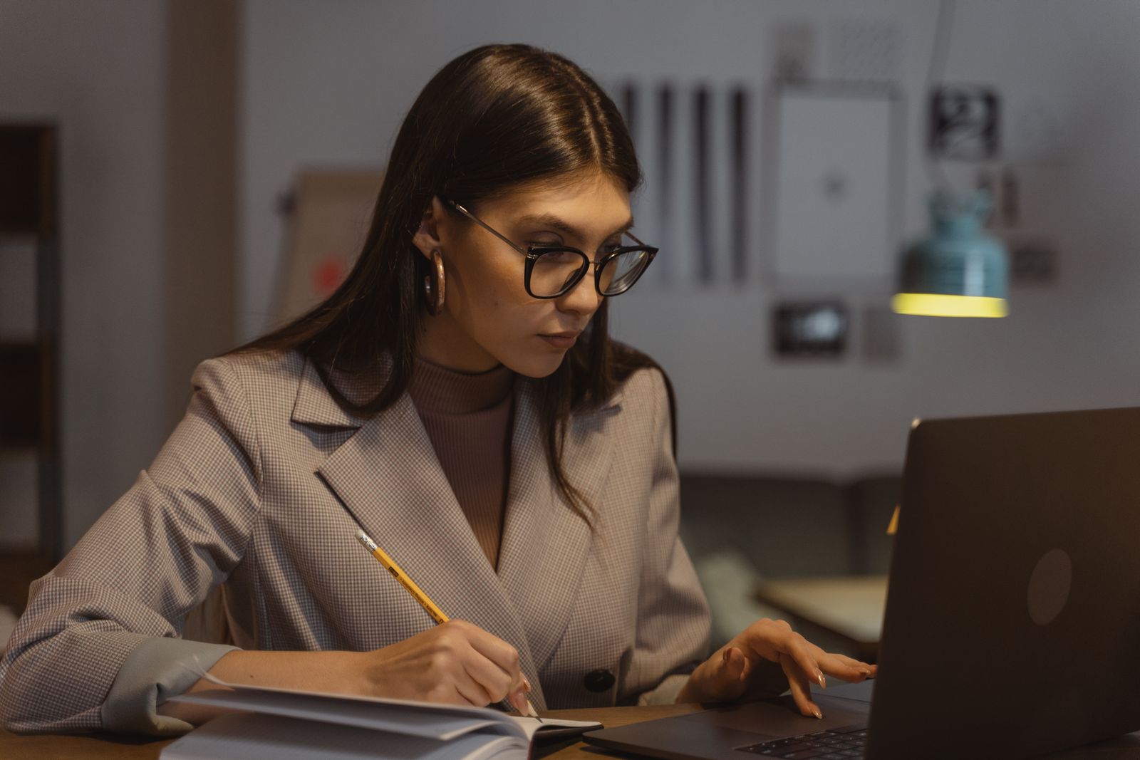 A woman in a blazer reviewing notes at her laptop