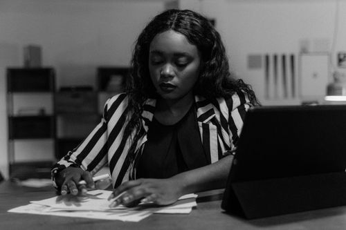 Free Black and white image of a businesswoman working diligently at her desk. Stock Photo