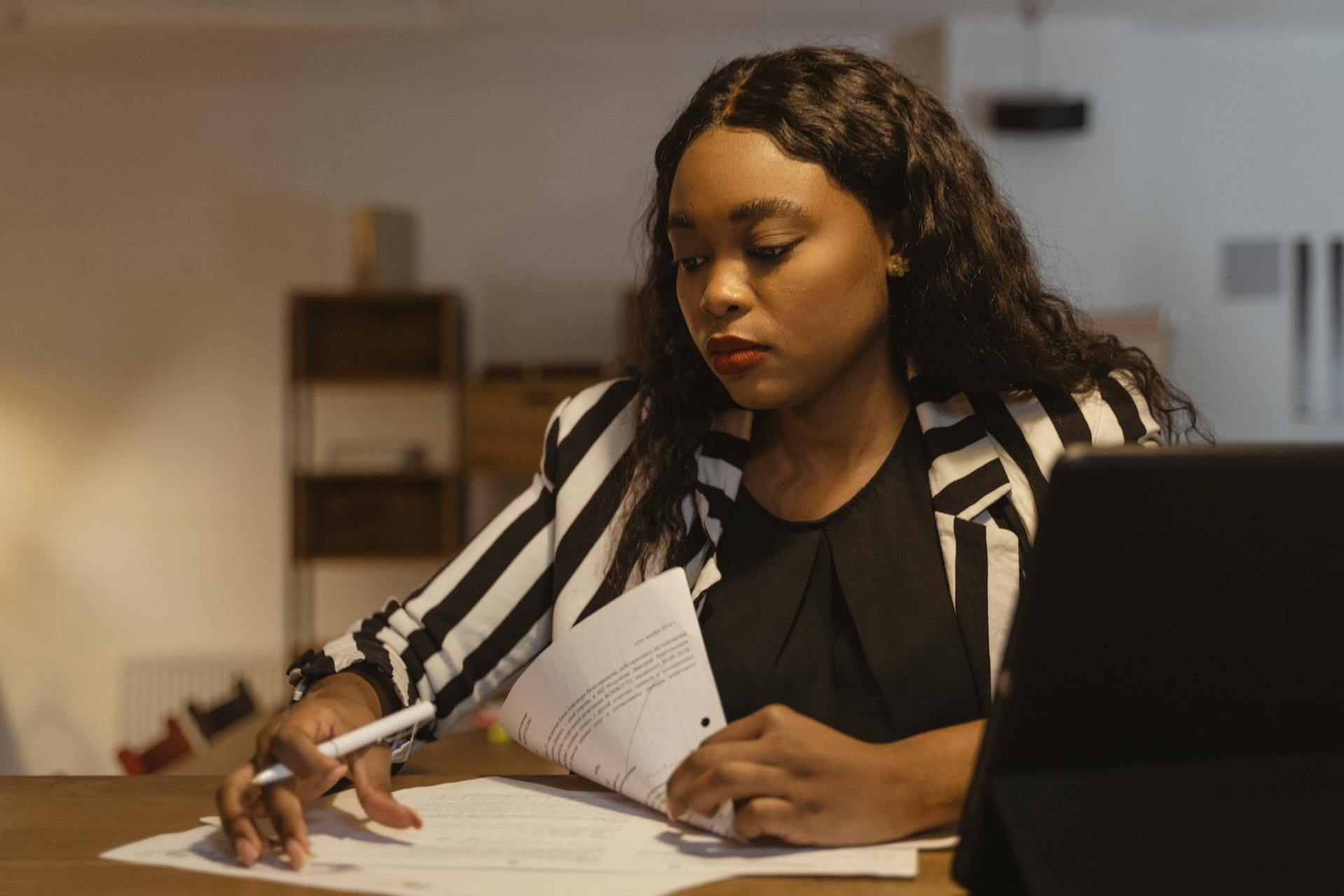 A businesswoman concentrating on paperwork at her office desk, highlighting leadership and focus.