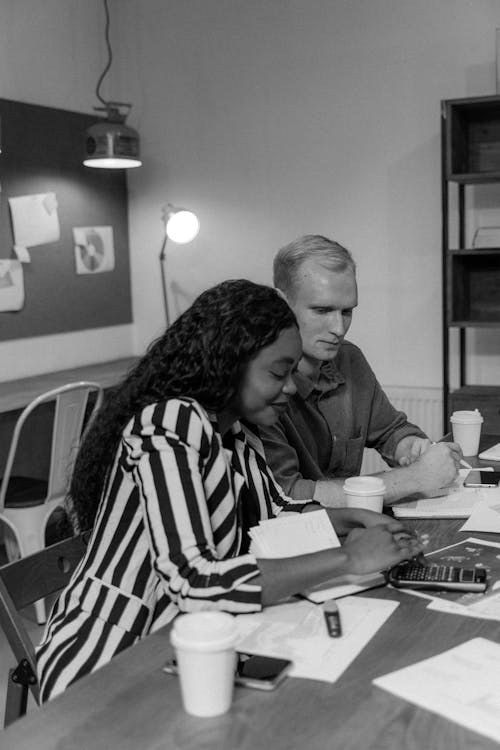 Grayscale Photograph of a Man Sitting Beside Woman