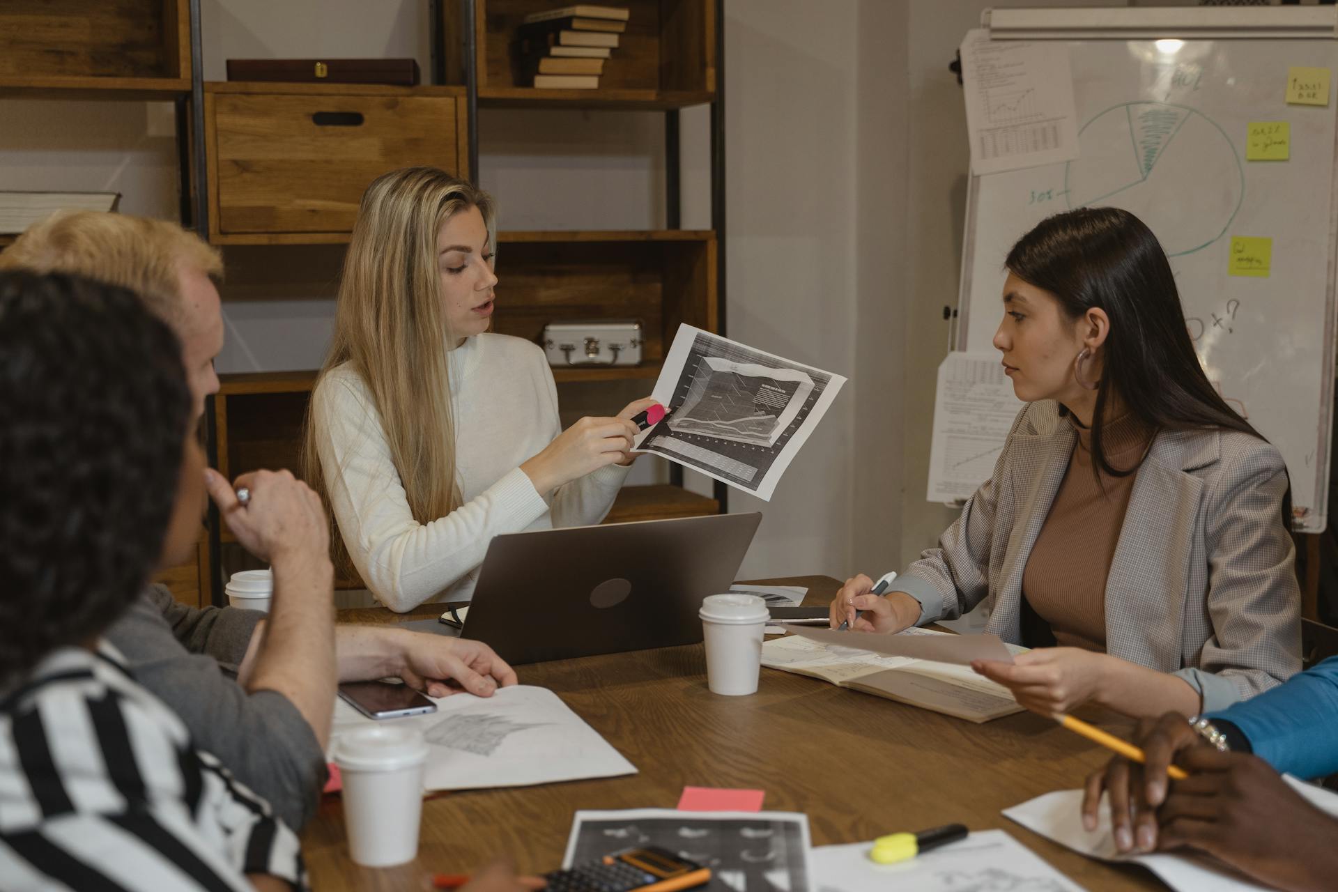 Group of professionals discussing business strategies around a table with documents and laptops.