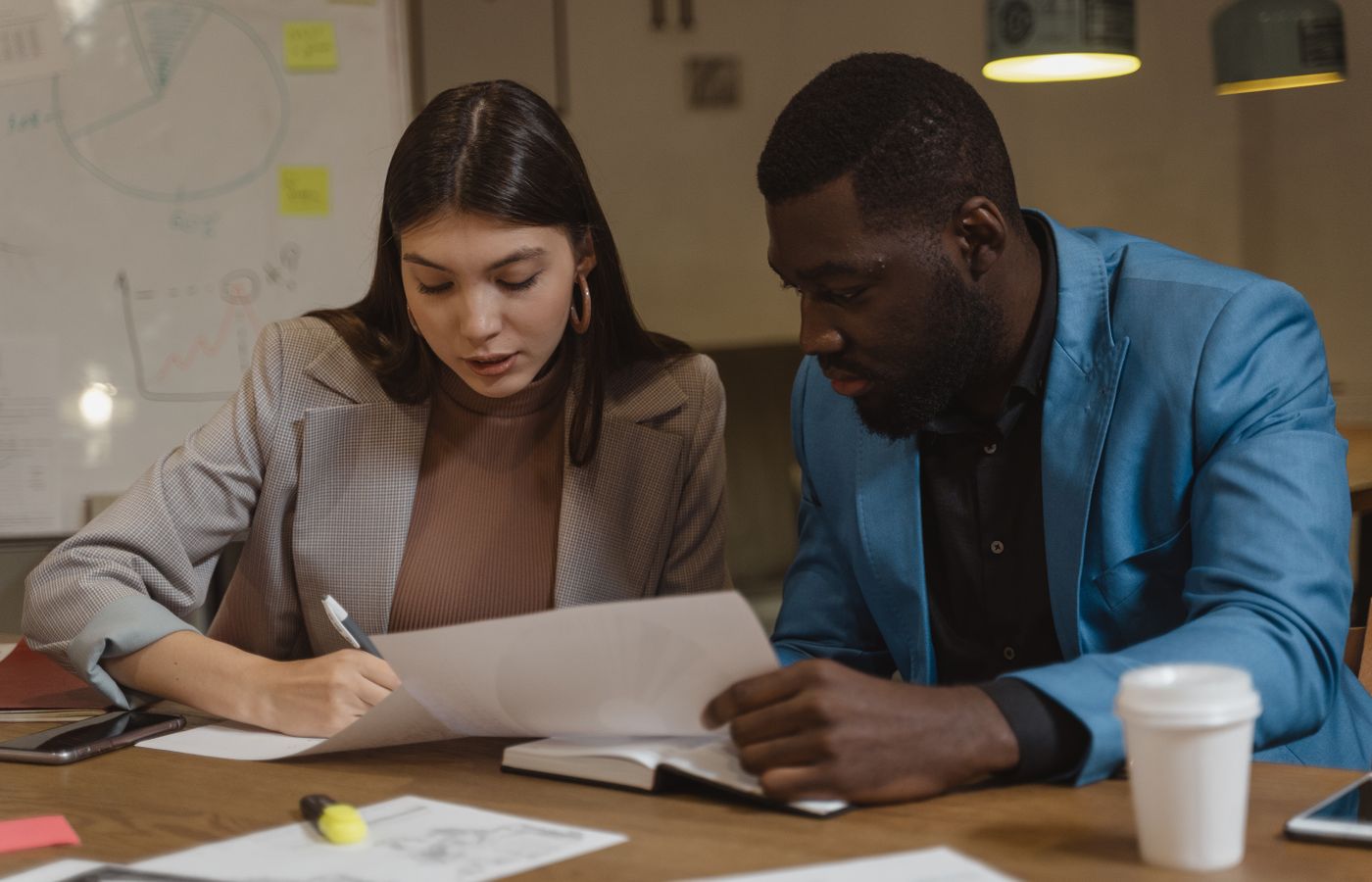 Two colleagues collaborating over documents at an office desk.