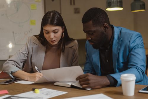 Free Two colleagues collaborating over documents at an office desk. Stock Photo
