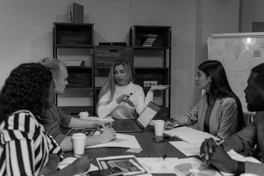 Black and white image of a diverse team engaged in a collaborative business meeting, fostering teamwork.