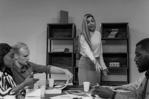 Monochrome image of a diverse team in a focused business meeting, collaborating around a table.