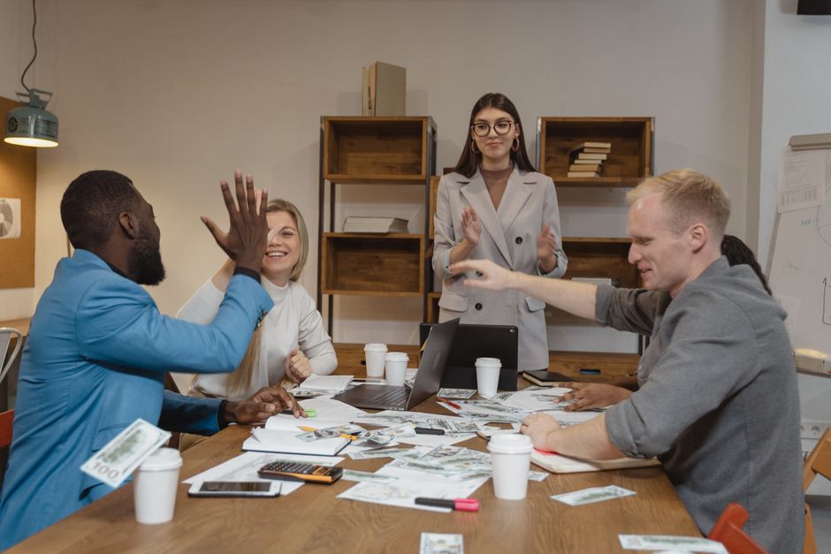 Un equipo multicultural disfrutando del éxito durante una reunión de negocios colaborativa en una oficina moderna.