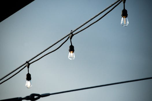 Close-up of hanging light bulbs on a cable outdoors against a clear sky.