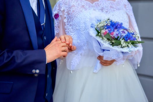 Elegant close-up of a bride and groom exchanging rings and holding a vibrant bouquet of flowers.