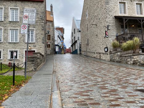 Charming cobbled street in Old Quebec City featuring historic stone buildings on a cloudy day.