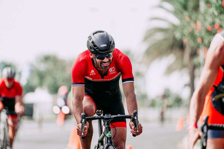 Smiling Muscular Cyclist Riding Bike During Race On Road