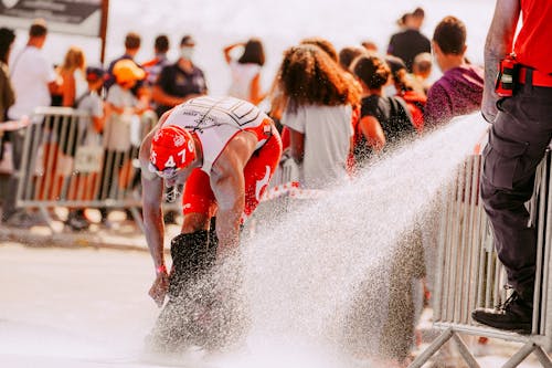 Free Crop anonymous man washing fins of sportsman in active wear using hose with fast water flow during competition Stock Photo