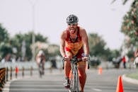 Fit sportsman in protective helmet and cycling glasses riding bicycle on road during competition