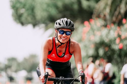 Free Smiling female cyclist in helmet and sunglasses wearing sportswear cycling on street in daytime Stock Photo
