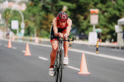 Full body of young cyclist in helmet and sportswear riding bicycle on asphalt road