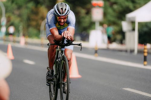 Free Full length of man in helmet riding bicycle fast on asphalt track during competition Stock Photo