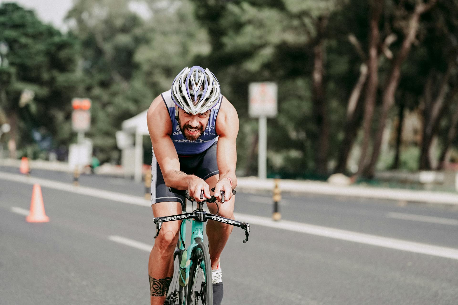 Focused cyclist racing on a highway in a competitive triathlon event, showcasing speed and determination.