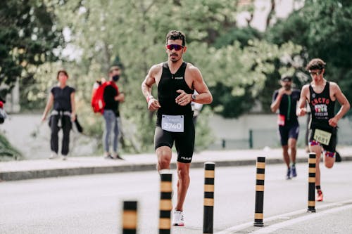 Full body of concentrated jogger running on asphalt track in city street during marathon