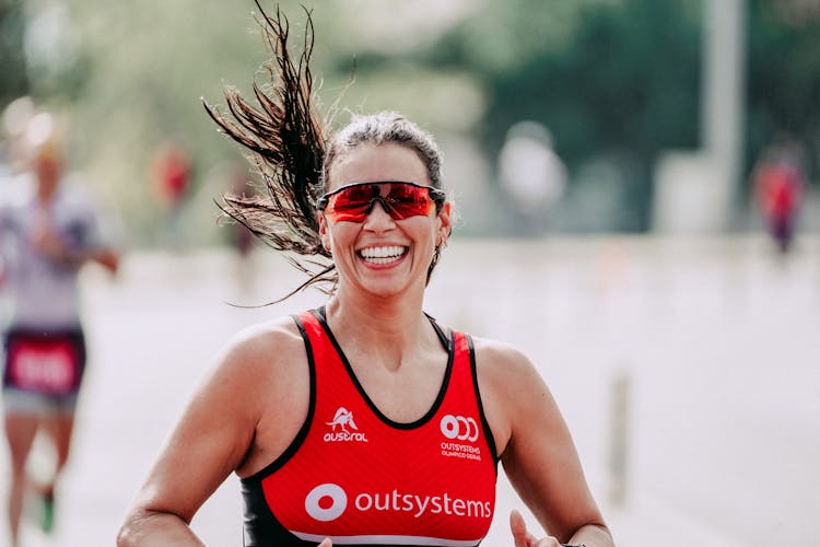 Cheerful Woman Running On City Track