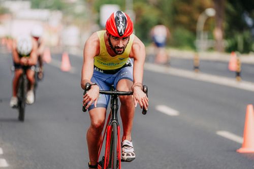 Free Concentrated bearded man in protective helmet and sportswear cycling on asphalt road and looking at camera Stock Photo