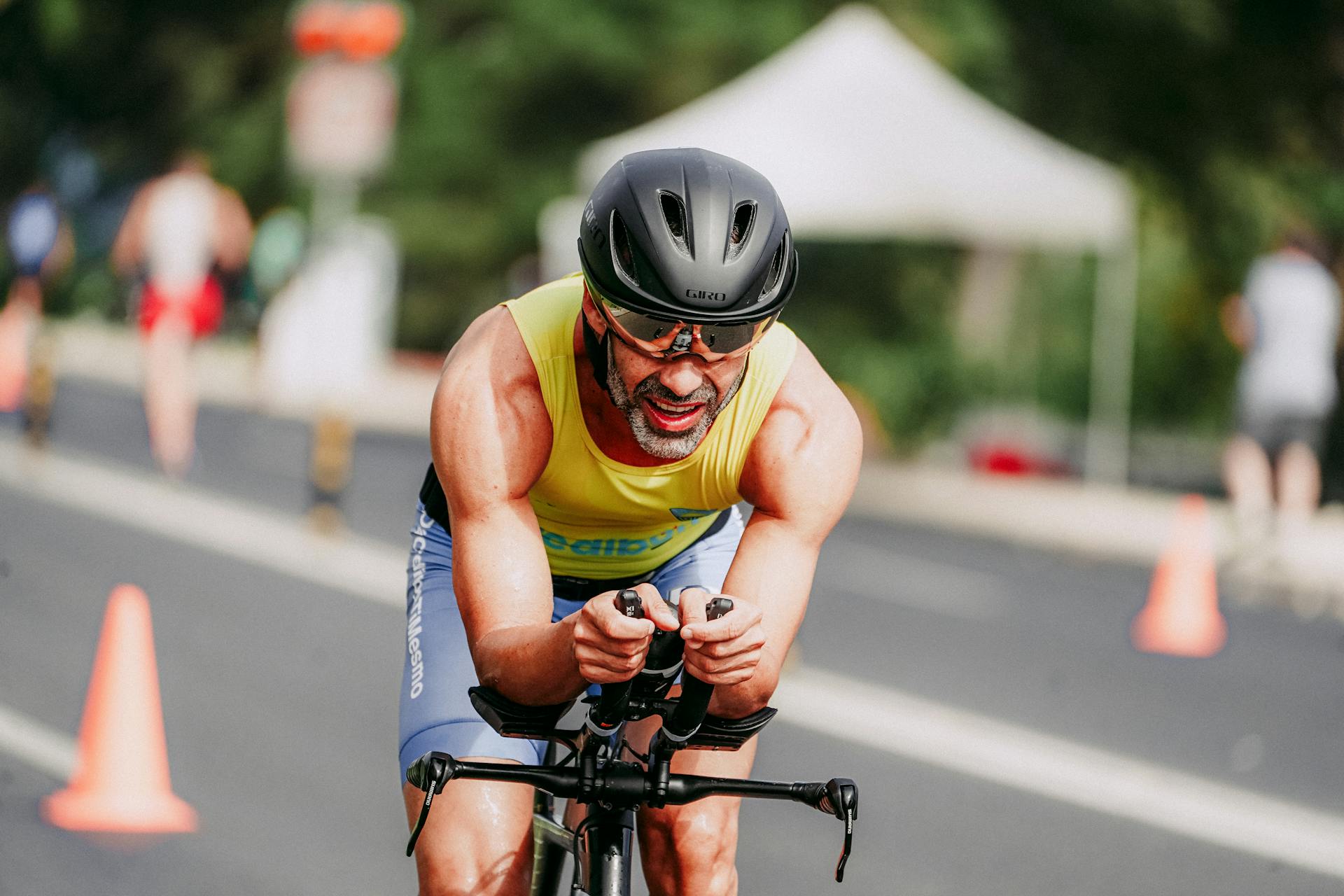 Smiling man in sportswear and helmet competing on bicycle riding on asphalt road