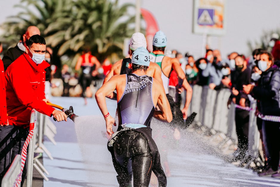 Triathletes running during a race, passing water station outdoors.