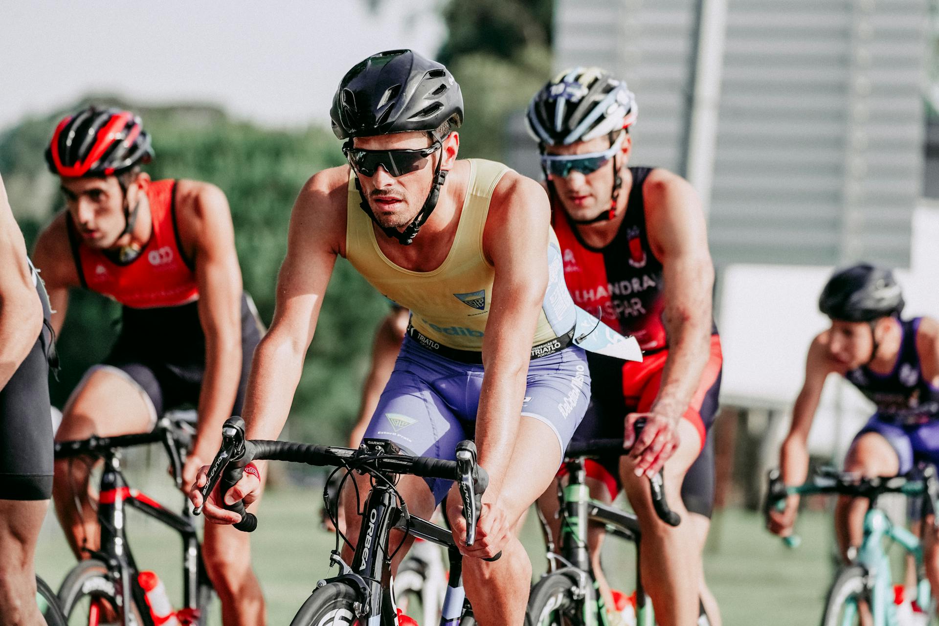 Group of people in protective helmets and sportswear riding bicycles on asphalt road during competition