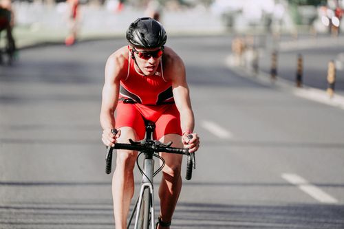 Free Strong cyclist in protective glasses and helmet riding bicycle on asphalt roadway during competition Stock Photo