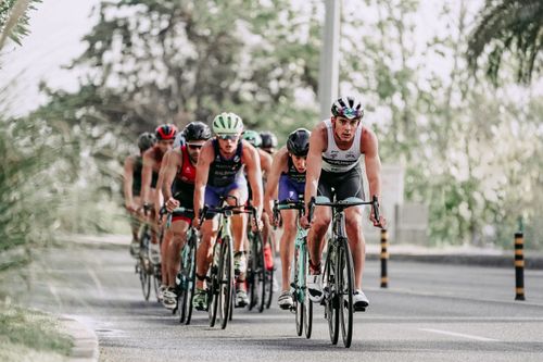 Free Full body of group of people in helmets and sportswear riding bicycles on asphalt road during race Stock Photo