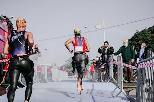 Free Back view of faceless group of people in wet sportswear running barefoot while taking part in competition Stock Photo