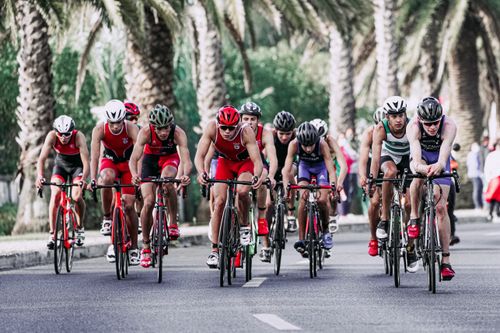 Free Group of people in protective helmets and sportswear riding bikes on asphalt road during competition Stock Photo