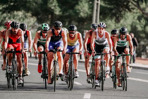 Free Full body of sportsmen in t shirts and shorts with helmets on heads riding bicycles on even paved road in summertime on blurred background Stock Photo