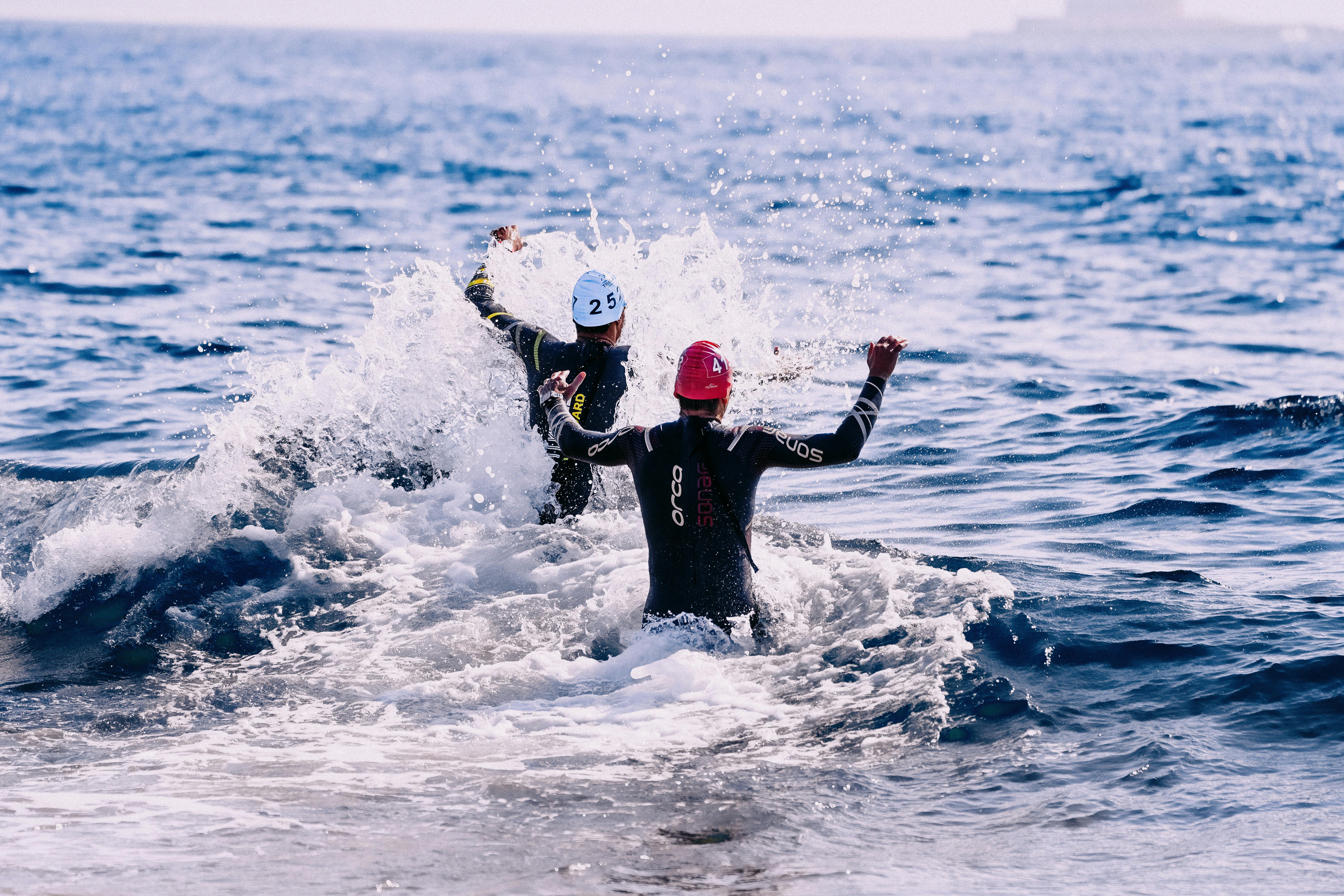 faceless people running into ocean in daytime